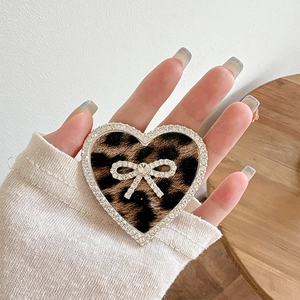 Close-up of heart-shaped phone grip with leopard print and rhinestone bow detail