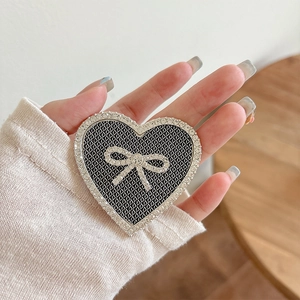 Macro shot of a black mesh heart phone grip with a sparkling rhinestone bow detail