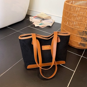 Retro large black tote bag with brown leather trim and fashion label on a chic tiled floor