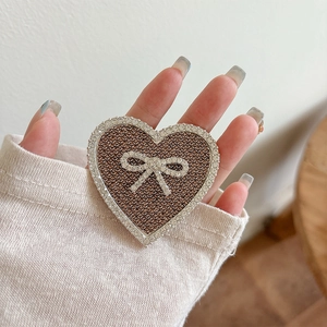Macro shot of heart-shaped phone grip with bowknot design and sparkling white rhinestones