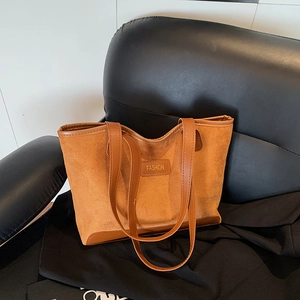 Retro caramel suede tote bag with leather trim and FASHION label on black sofa