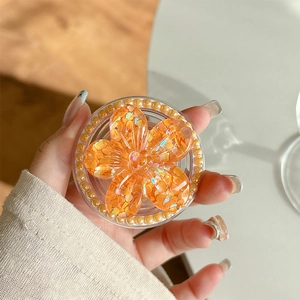Detail of flower phone grip with orange sequins and faux pearl trim decoration
