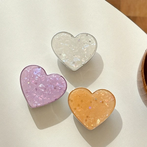 Detail view of heart-shaped phone grips with star sequins and shimmering glitter texture