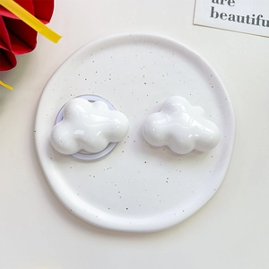 Close-up of white cloud-shaped phone grip on a decorative ceramic plate with cards