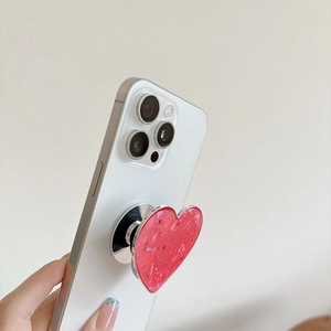 Red heart phone grip with star sequins and silver base on a white smartphone