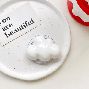 Close-up of a glossy white cloud-shaped phone grip on a decorative white marble plate