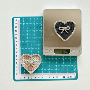 Macro detail of rhinestone bow heart grip showing 5.5cm width and 22.4g weight