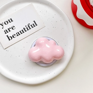 Detailed view of glossy pink cloud phone grip stand on a decorative ceramic tray
