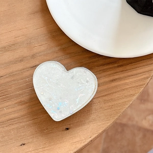 Detail of heart-shaped phone grip with iridescent white finish and star sequins
