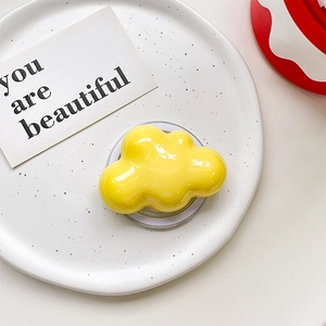 Macro shot of yellow cloud-shaped phone grip with glossy resin finish on ceramic tray