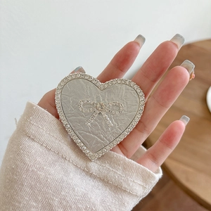 Detail of heart-shaped phone grip with silver crinkle texture and rhinestone bow