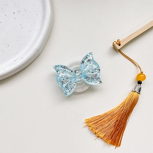 Detail of light blue glitter butterfly phone grip on textured beige leather surface