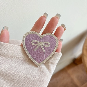Macro view of purple faux leather heart phone stand with rhinestones and bow detail