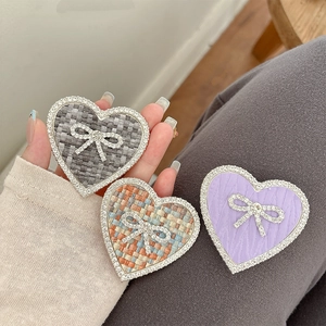 Macro detail of heart-shaped phone grips with tweed fabric and rhinestone bow accents