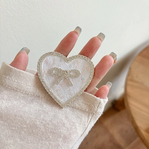 Macro shot of heart-shaped phone grip with glitter, rhinestones and a crystal bow detail