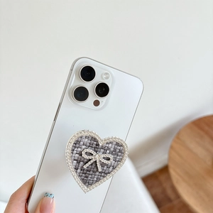 Handheld heart-shaped rhinestones phone socket with bowknot on white smartphone