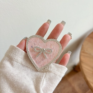 Detail shot of heart-shaped phone grip with pink glitter and rhinestone bow accent