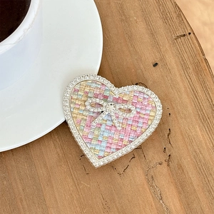 Macro shot of heart-shaped rhinestone phone grip with pink tweed and crystal bow detail