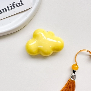 Detail of a glossy bright yellow cloud phone grip with smooth polished finish and reflections