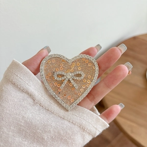 Close-up of heart-shaped phone grip with glitter and a rhinestone bow detail