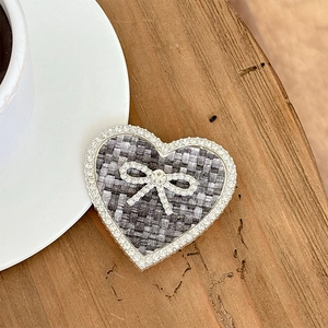 Detailed view of heart-shaped tweed phone grip with rhinestone bow on wooden table