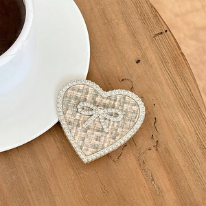 Detail of heart-shaped phone grip featuring tweed fabric, rhinestones and a crystal bow