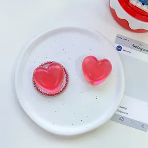 Detail showing two red heart-shaped resin phone grips on a decorative white plate
