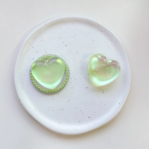 Detail of heart-shaped iridescent phone sockets with pearl bead edges on a ceramic tray