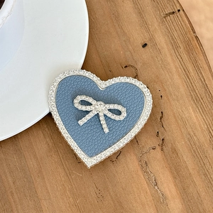 Close-up of light blue leather heart phone grip with rhinestone bow on wooden table