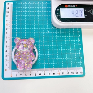 Macro detail of purple glitter bear phone stand showing dimensions and 42.7g weight