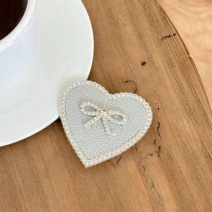 Detail of a heart-shaped phone grip with sparkling rhinestones and a small bow decoration