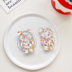 Macro shot of cute glitter bear phone socket stands with heart sequins on white plate
