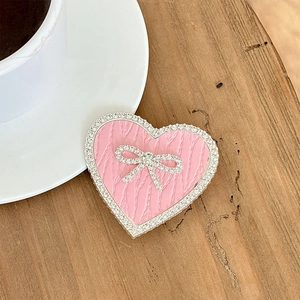 Close-up of heart-shaped phone grip with pink knit texture and sparkling rhinestones