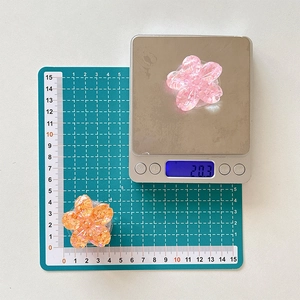 Detail showing weight and size of flower phone grip with colorful sequins on scale