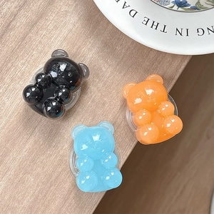 Jelly bear phone socket stand in black, light blue and orange on wood surface