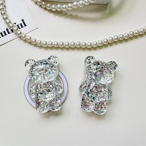 Close-up of glitter-filled resin bear phone grip with adhesive base on white surface