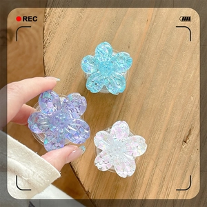 Three sequined cherry blossom phone sockets in blue, purple, and white on a wood table