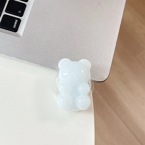 Close-up of a white jelly bear phone grip stand on a minimalist white desk setup
