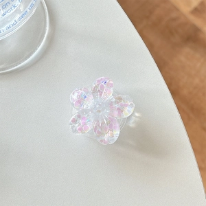 Close-up of 3D resin flower phone grip with pink heart sequins and glitter on white desk