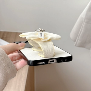 Detail view of leather cream phone case with bow stand, pearl accent and precise cutouts