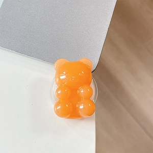 Macro shot of an orange translucent gummy bear phone grip on a white desk