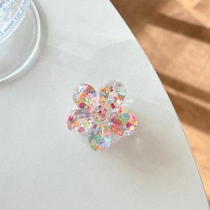 Close-up of a floral phone grip filled with colorful heart-shaped sequins on a white desk