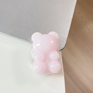 Macro detail of a translucent pink jelly bear phone grip mounted on a laptop edge
