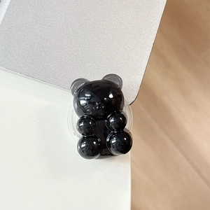 Glossy black gummy bear phone grip with transparent expandable stand on silver laptop