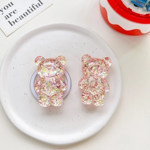 Macro view of transparent pink resin bear phone grip filled with laser sequins