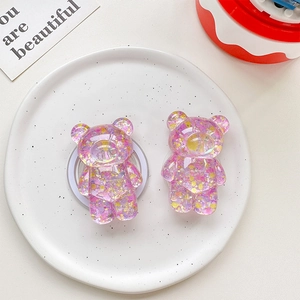 Detail of two purple glitter bear phone grips with sequins on a ceramic tray