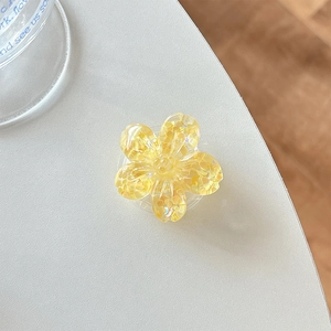 Detailed macro shot of a yellow sequin flower phone grip on a white textured desktop