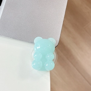 Macro view of a light blue translucent jelly bear phone grip on a silver laptop surface