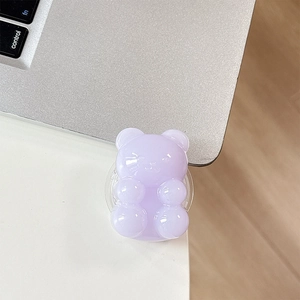 Close-up of a translucent purple gummy bear phone grip stand on a white desk