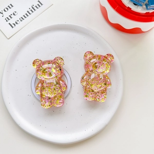 Detail of pink glitter bear phone grips on white ceramic plate with soft lighting